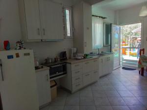 a kitchen with white cabinets and a refrigerator at Trizinia View Garden in Galatas +13 photos