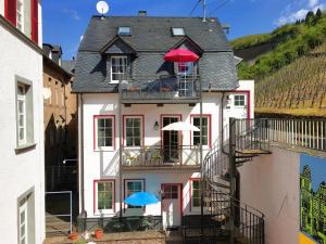 un edificio blanco con 2 sombrillas en el balcón en Mosel Ferienhaus Reblaus, en Zell an der Mosel