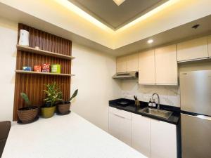 a kitchen with white cabinets and a stainless steel refrigerator at Cozy Studio Unit in Abreeza Place Tower 1 with parking in Davao City +10 photos