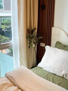 a bedroom with a bed and a window with a plant at Cozy Studio Unit in Abreeza Place Tower 1 with parking in Davao City