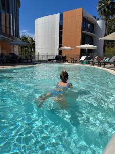 a woman is swimming in a swimming pool at SoBlue Hôtel in Antibes