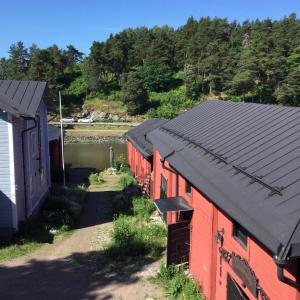 a red barn with a black roof next to a building at Remuganes suite - Porvoon Linna in Porvoo