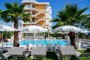 a hotel with a swimming pool and palm trees at Hotel Belvedere in Martinsicuro
