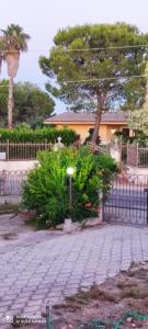 a fence and some bushes and a tree at Il giardino del Sole in Galatone