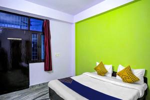 una camera da letto con parete verde e un letto con cuscini gialli di SPOT ON Raj Hotel Vip Near Worlds Of Wonder a Kālkāji Devi