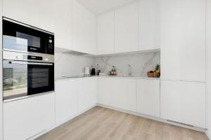 eine weiße Küche mit weißen Schränken und schwarzen Geräten in der Unterkunft 13 Esteva Resorts 2ºE Aljezur 5 min to the Beach in Aljezur