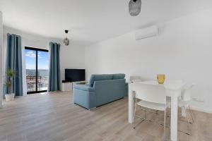 ein Wohnzimmer mit einem blauen Sofa und einem Tisch in der Unterkunft 13 Esteva Resorts 2ºE Aljezur 5 min to the Beach in Aljezur