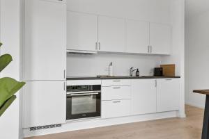 a white kitchen with white cabinets and a sink at Cosy 4-Person Apartment in The Heart of Aarhus in Aarhus