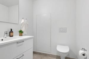 a white bathroom with a toilet and a sink at Cosy 4-Person Apartment in The Heart of Aarhus in Aarhus