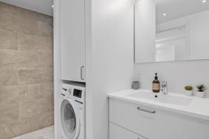 a white bathroom with a washing machine and a sink at Amazing 2BR w Balcony in the Heart of Aarhus City in Aarhus