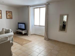 a living room with a television and a couch at La Romance de Grignan in Grignan