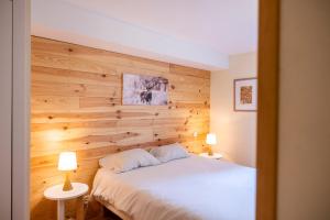 a bedroom with a wooden wall with a bed and two lamps at T2 au cœur du centre historique de Briançon #1 in Briançon