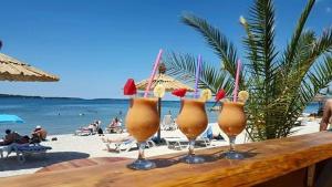 a wooden table with four wine glasses on a beach at Deluxe apartment Playa in Valbandon