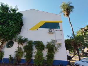 a white building with a window and a palm tree at Hotel INDI in Ribeirão Preto
