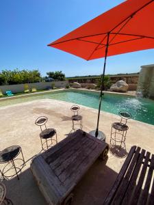 a wooden bench with chairs and an umbrella next to a pool at Belle maison piscine in Arles