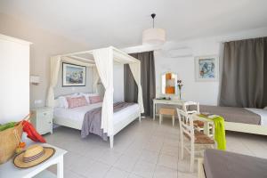 een slaapkamer met twee bedden, een tafel en een bureau bij Villa Porto Rondo in Agios Prokopios