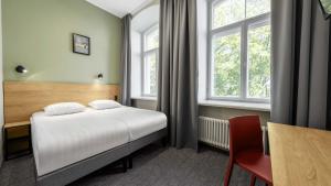a bedroom with a bed and a desk and window at Rija Old Town Hotel in Tallinn