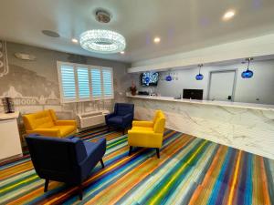 a waiting room with yellow chairs and a colorful carpet at Hotel Rudra - Hollywood in Los Angeles