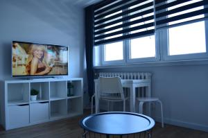 Una sala de estar con un televisor y una mesa. en Apartment Silesia Park - Free Parking - easy check-in, en Katowice