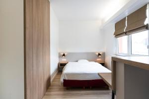 a small bedroom with a bed and a window at Logis H&ocirc;tel Acacia in Esch-sur-Alzette