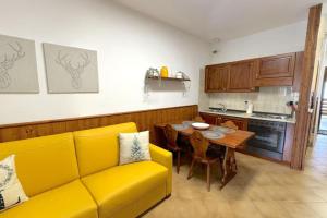 a living room with a yellow couch and a table at The Capriolo home in Tarvisio