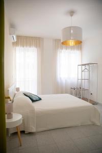 a white bedroom with a large bed and a chandelier at Green rooms in Bari