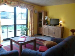 a living room with a blue couch and a tv at Schönes Ferienhaus in Althagen mit Terrasse und Grill in Ahrenshoop