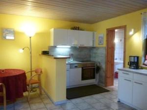 a kitchen with yellow walls and a table with a lamp at Schönes Ferienhaus in Althagen mit Terrasse und Grill in Ahrenshoop