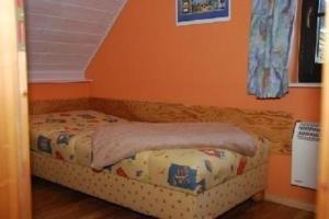 a small bed in a bedroom with an orange wall at Schönes Ferienhaus in Althagen mit Terrasse und Grill in Ahrenshoop