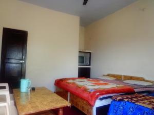 Zimmer mit einem Bett, einem Tisch und einer Mikrowelle in der Unterkunft Snow View Guest House Kausani & homestay in Kausani