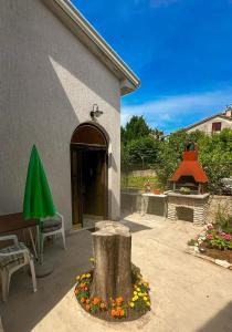 a patio with a tree stump and a table and a green umbrella at Apartment Oja in Malinska