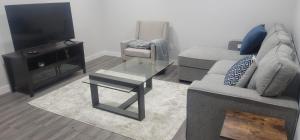 カルガリーにあるA Cozy home away from home at South East Calgaryのソファ、テレビ、テーブルのあるリビングルーム