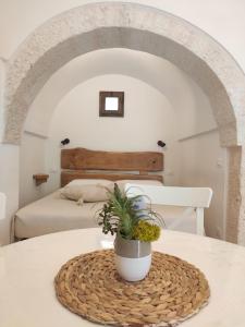 a bedroom with a bed and a table with a potted plant at Trullo al vicoletto al civico 10, civico 8, civico 7 in Alberobello
