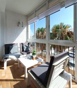 a living room with white furniture and large windows at Tropicana Suite con salida directa al mar y piscina in Roquetas de Mar