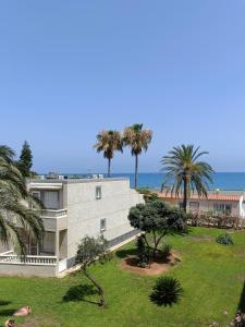 a building with palm trees in front of the ocean at Tropicana Suite con salida directa al mar y piscina in Roquetas de Mar