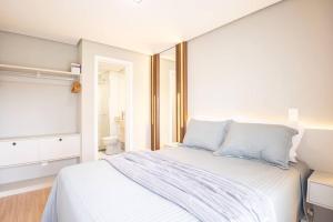 a bedroom with a large white bed with blue pillows at Apto 306 Inn com vista Parque Una e garagem in Pelotas
