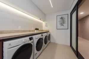 a laundry room with three washing machines and a counter at Apto 306 Inn com vista Parque Una e garagem in Pelotas