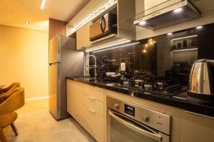 a kitchen with a stove and a refrigerator at Apto 306 Inn com vista Parque Una e garagem in Pelotas