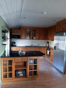 a kitchen with wooden cabinets and a stainless steel refrigerator at Sentralt, kort vei til byens fasiliteter in Molde