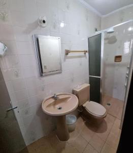 a bathroom with a sink and a toilet and a mirror at Apartamento Centro - Jardim Caiahu - in Mongaguá +11 photos