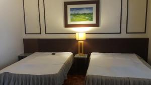 2 camas en una habitación con una lámpara y una foto en Jalan Kamus, Simpang Empat Holiday home, en Kampong Pulau Sebang