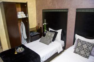 a bedroom with two beds and a table and a chair at Hotel Vents Des Iles in Essaouira