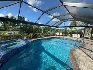 a swimming pool with an umbrella over it at Fun In The Sun: Canal Access in Cape Coral