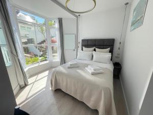 a white bedroom with a large bed with white sheets at Henrys in St Ives