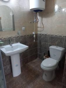 a bathroom with a white toilet and a sink at Hotel TEM in Khorog