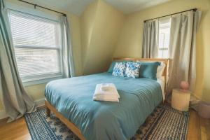a bedroom with a bed with blue sheets and a window at Tufts 4BDR-15-MIN to Harvard&Boston-Free Parking in Somerville