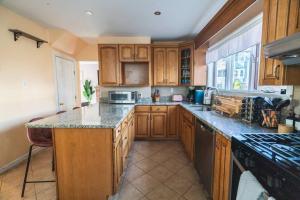 a kitchen with wooden cabinets and a counter top at Tufts 4BDR-15-MIN to Harvard&Boston-Free Parking in Somerville +21 photos
