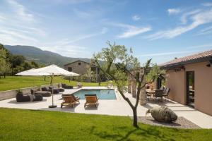 un patio trasero con piscina con sillas y sombrilla en Villa Bagnoli, en Boljun