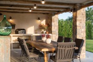cocina al aire libre y comedor con mesa de madera y sillas en Villa Bagnoli, en Boljun