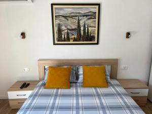 Apartmani Mareta في بتروفاتس نا مورو: سرير والمخدات صفراء ولوحة على الحائط